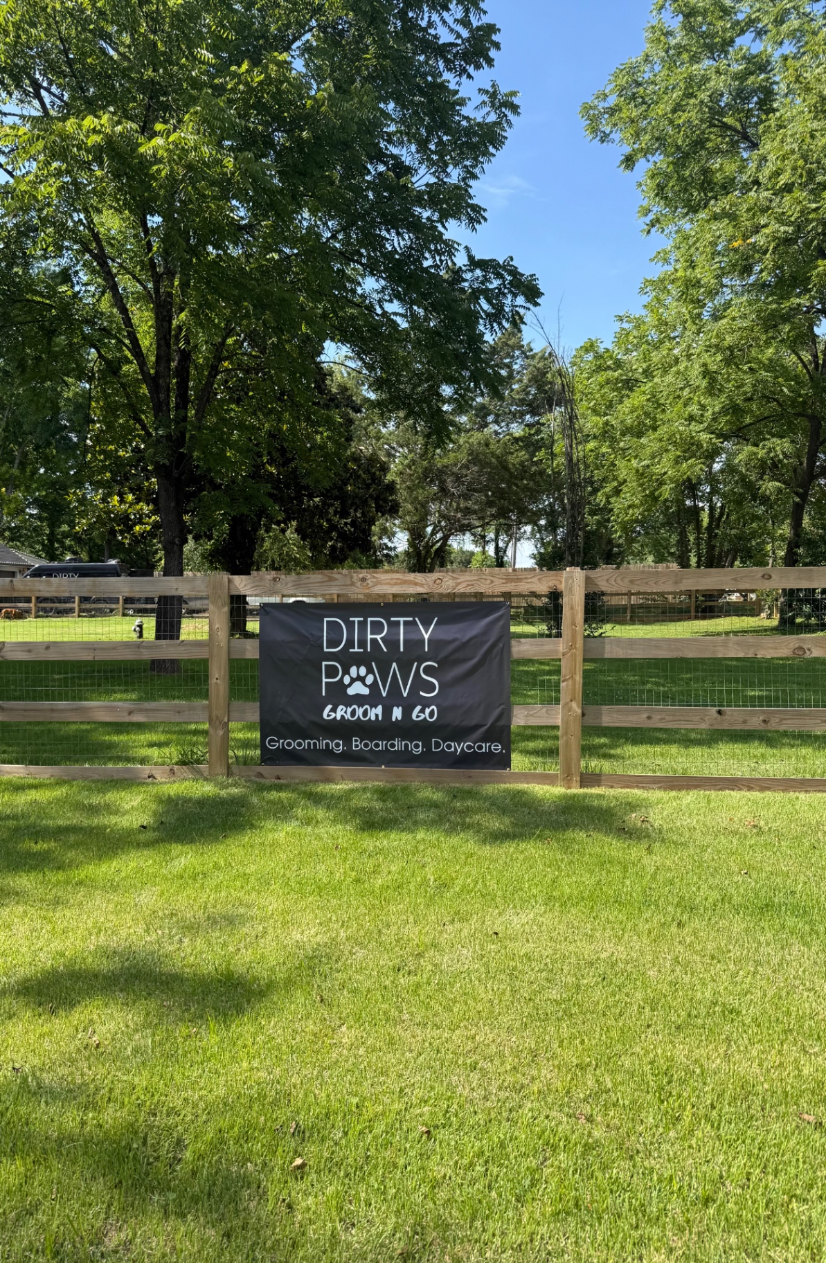 Dirty Paws Groom n Go sign on the fenced acre of grass used for dog boarding and daycare in Murfreesboro, TN
